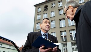 Sachverständiger im Gespräch mit Eigentümer vor Bestandsgebäude